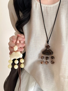 Détail du collier pendentif nuage en résine avec glands de perles sur cordon minimaliste