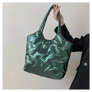 Detail of green quilted tote bag with double handles and a fashion label decoration