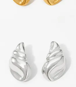 Detailed macro view of polished conch shell shaped earrings in glossy silver and gold finish