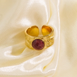 Retro gold titanium steel open ring featuring a red gemstone on yellow silk background