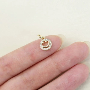 Macro detail of a small gold plated smiley face pendant with inset sparkling crystals