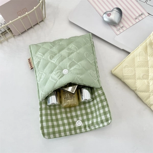 Dettaglio pochette trapuntata cuore verde con bottone a pressione e fodera a quadri