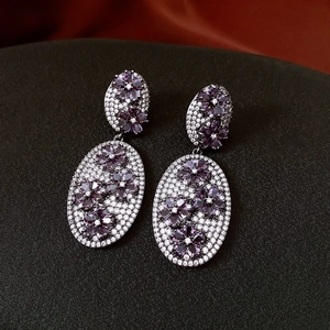 Macro detail of vintage floral drop earrings with purple crystals and silver finish