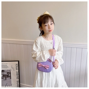Detail of a purple round crossbody bag for girls with a pink sequin bow on white dress