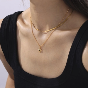 Classic gold layered necklace with star pendant and green gemstone on woman neck