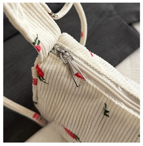 Detail of smooth metal zipper on strawberry print corduroy bag with soft texture