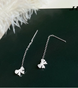 Macro view of S925 sterling silver bow earrings with detailed tassel chain and hallmark