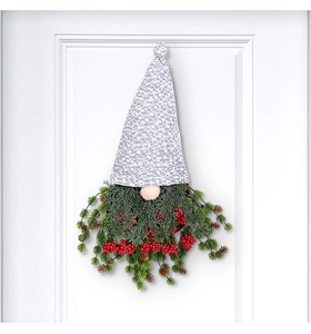 Gros plan d'une couronne de gnome de Noël avec branches de pin et baies rouges sur porte