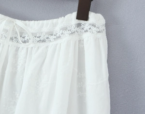 Détail de la taille élastique avec broderie et cordon sur une jupe blanche en dentelle