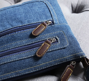 Detail view of durable blue denim fabric with brown leather pulls and yellow stitching