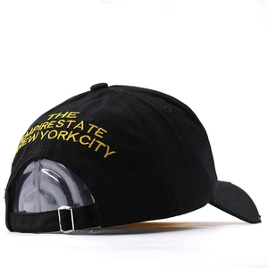 Detail of adjustable silver metal buckle and yellow embroidery on a black cotton baseball cap