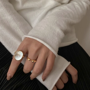 Elegant gold open ring set with large oval mother of pearl on a woman's finger