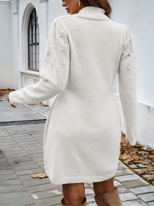 Détail d'une robe en maille blanche avec perles sur les manches et les épaules en extérieur