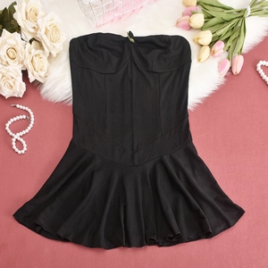 Detail shot of black ribbed strapless top with ruffled hem on soft texture background
