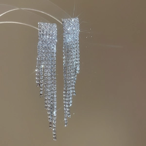 Gros plan de boucles d'oreilles à pompons argentées avec strass scintillants