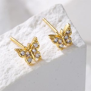 Vista macro de pendientes de mariposa bañados en oro de 18K con circonitas brillantes