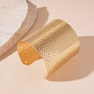 Detailed view of wide golden cuff bracelet featuring unique honeycomb hammered texture