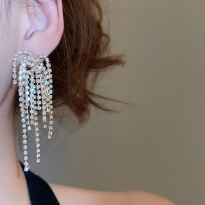 Detailed view of elegant gold tassel earrings with sparkling rhinestones on model
