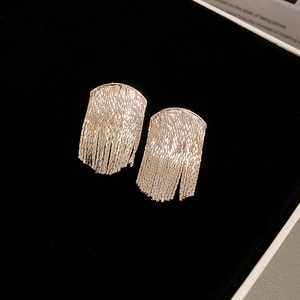 Detailed close-up of silver geometric fan-shaped tassel earrings on black background