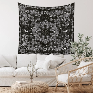 Detailed close-up of a bohemian black and white mandala tapestry on a white living room wall