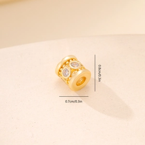 Macro shot of 0.8cm gold metal bead with zircon inlay and detailed hollow patterns