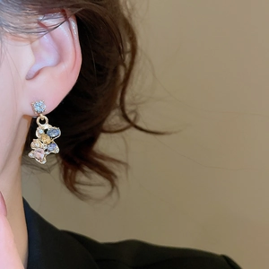 Close-up of golden horse pendant earring with colorful zircons worn by a model