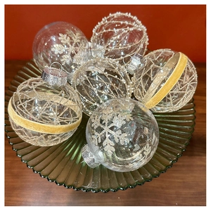 Close-up of champagne lace lace and glitter dotted Christmas tree ornaments in a glass bowl