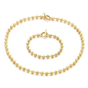 Golden beaded necklace and bracelet set with minimalist toggle clasp on white background