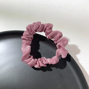 Detail showing the glossy texture and pleated design of the pink satin scrunchie accessory