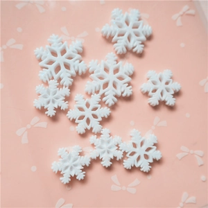 White resin snowflake charms for DIY phone cases and hair accessories on pink background