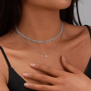 Close-up of double-layered silver cuban chain necklace with zircon letter B pendant