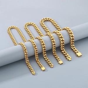 Polished gold stainless steel Cuban link chains displayed on a minimalist gray holder