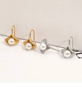 Detailed view of ginkgo leaf earrings with pearls in gold and silver finishes