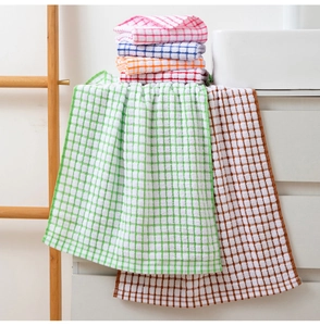 Close-up of six colorful plaid cotton tea towels stacked on a bright kitchen counter