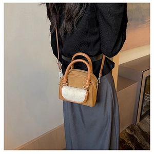 Detail of a brown faux suede handbag with white faux shearling pocket and silver hardware