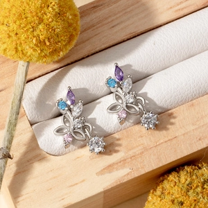 Floral zircon stud earrings with colorful stones and white drops in a wooden jewelry box