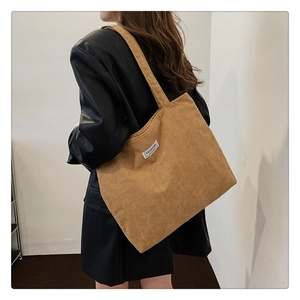 Close-up of brown corduroy tote bag featuring a Fashion label on black leather jacket