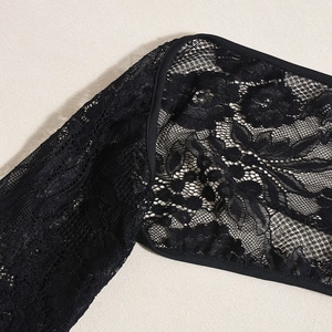 Close-up of black floral lace fabric with detailed stitching on a beige leather surface