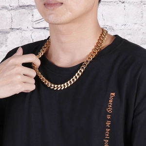 Close-up of a thick gold stainless steel Cuban link chain necklace worn by a male model