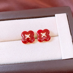 Detailed close-up of red enamel flower earrings with gold plating and center crystal