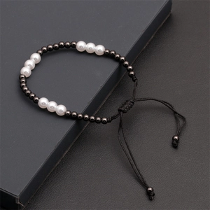 Detail view of hand-woven beaded bracelet with white pearls and black metallic beads