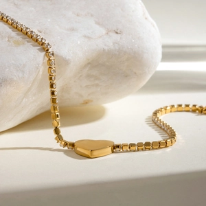 Detailopname van gouden hartarmband met zirkonia op een getextureerde steen