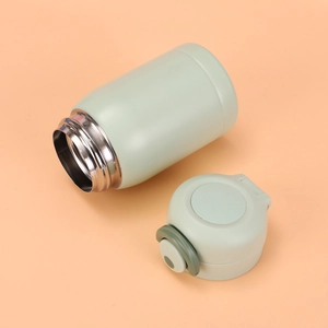 Detailed view of stainless steel vacuum flask interior and green pop-up lid