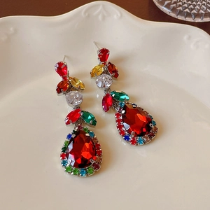 Macro detail of long earrings with colorful crystals and a large red pear-shaped gemstone
