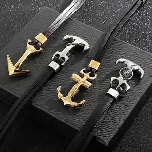 Detail view of anchor pendants with compass motifs on multi-layer leather bracelets