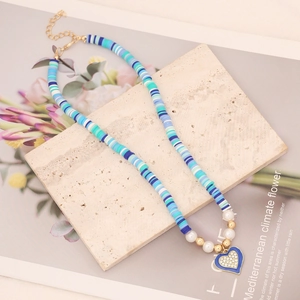 Detail of blue clay bead necklace featuring a sparkling heart pendant on marble stone