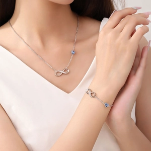 Detail showing infinity symbol and blue heart charm bracelet on a woman's wrist