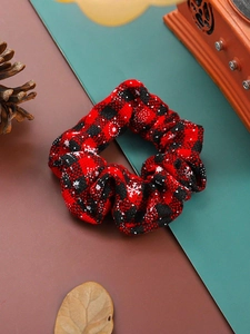 Detail of red and black plaid Christmas scrunchie with snowflake patterns and pine cones