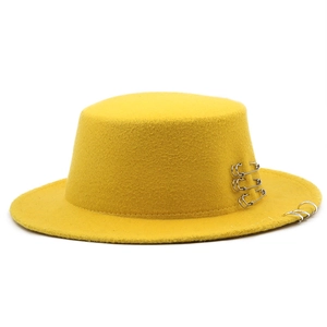 Detail of yellow wool flat top hat featuring silver safety pins and metal rings decor