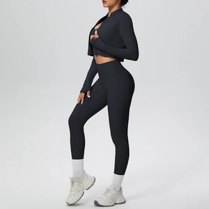 Vista laterale della giacca cropped nera con zip e dei leggings a vita alta sul modello